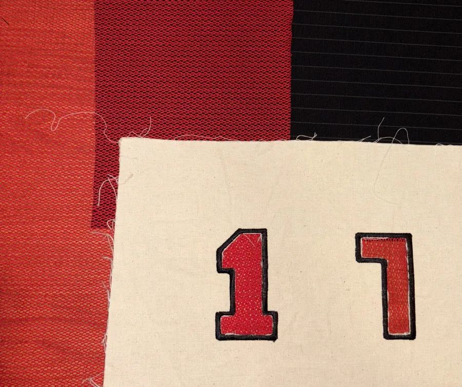 Red knit number appliqués on cream canvas, next to red and black knits.