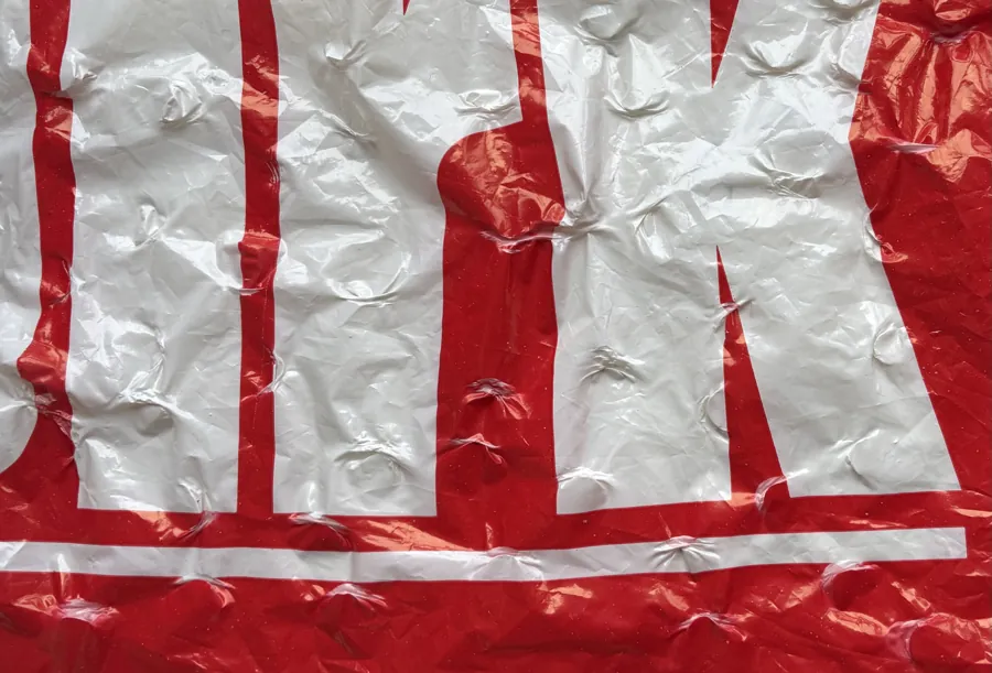 Close-up of a crumpled red and white printed plastic bag.