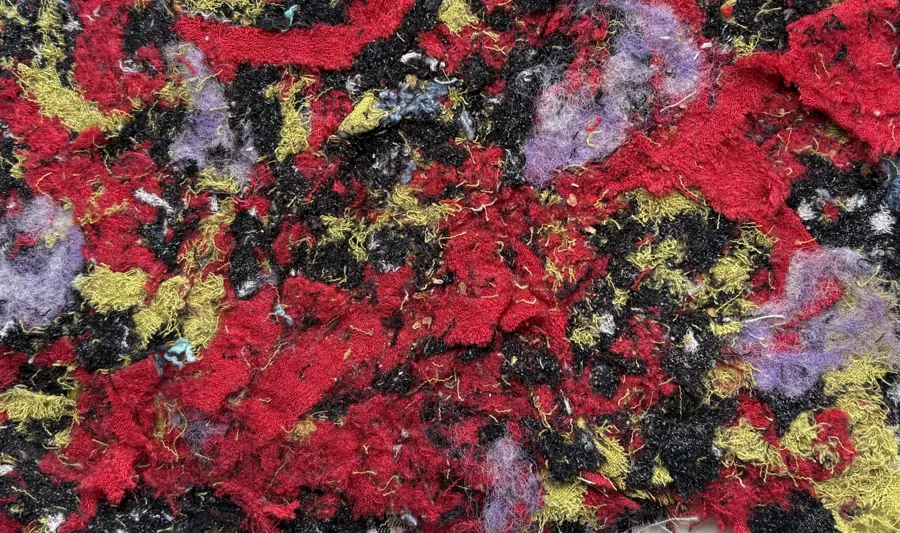 Felted recycled fibres in red, black, yellow and lilac.